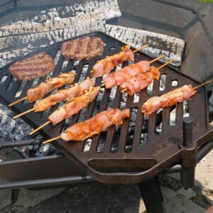 Plate BBQ grill with burgers and skewers over the fire