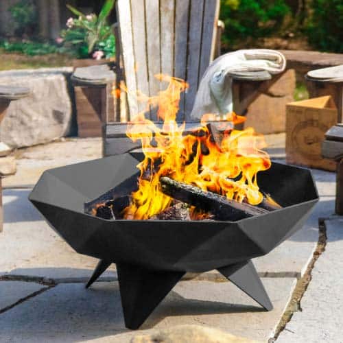Faceted polygon fire bowl burning on flagstone patio.